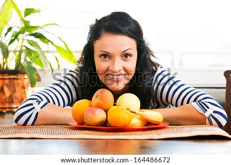 Young woman sitting at the table with fruits in front.