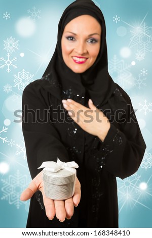 Model dressed in traditional Arabic style, holding Christmas present box.