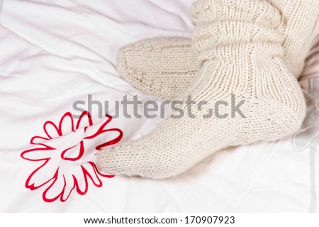 Legs in knitted warm socks, on bed.