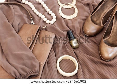 Stylish woman outfit. Brawn dress, shoes, white jewelry and purse, top view.