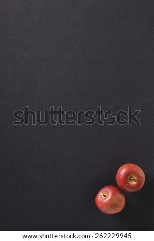 Red apples on a structured black background,with own shadows.