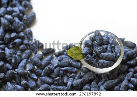 Honeysuckle blue berry fruits in a glass bowl on white background top view