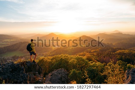 A hiker walking on a mountain meadow in spring or autumn. Hiking in the Lusatian mountains. Hiker, Backpacking on top of a mountain cliff landscape and trekking in it. Concept: Adventure, Art, Travel