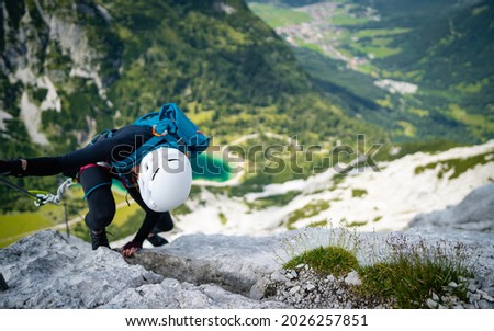 Woman climbs high on rock. Pretty, female climber on a via ferrata - climbing on a rock in Tajatkopf Klettersteig. Taken from mountain Tajakopf near Leermos ehrwald austria alps Imagine de stoc © 