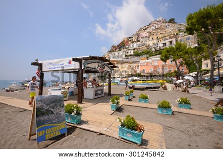 POSITANO ITALY - JULY 13, 2015 - A boy walks by a boat rental booth on the public beach in Positano