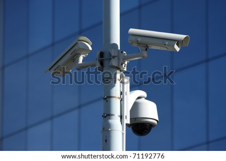 three security cameras on front of glass building