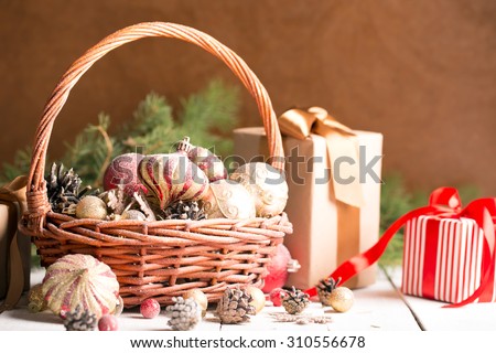 Christmas basket with red and golden ornaments, fir-cones on a wooden table