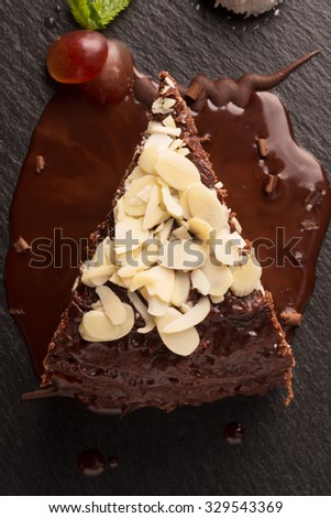 Piece of chocolate cake with almond,chocolate sauce and grapes