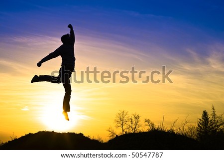 Man in the sunset, happy and jumps.