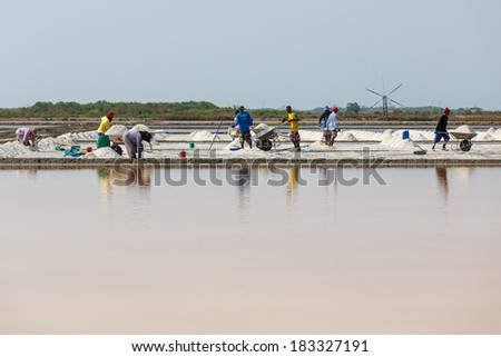 SAMUTSAKORN,THAILAND -APRIL 15: The workers are moving the raw salt to the store at Rama II road on April 15,2013 in Samutsongkram, Thailand. Samutsongkram is a big salt production area of Thailand