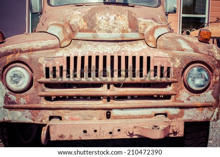Old truck rusting outside on a sunny day.