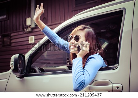 happy young woman talk on cell phone sitting in car