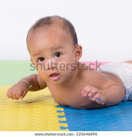 Happy cute 5 month old Asian baby boy with short black hair on rubber floor