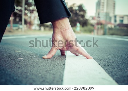Close-up hand businessman on a track ready to running, process color