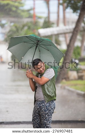 young man with umbrella in storm rainy