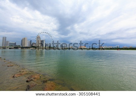 Big ferris wheel in the modern city skyline and bay water on front, Singapore.