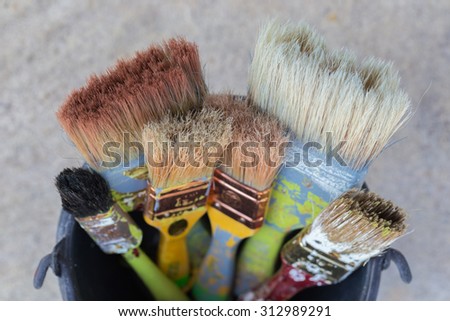 Close up old paint brushes in a bucket