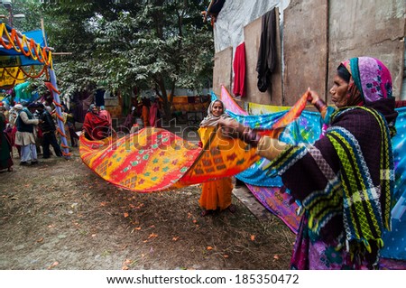 KOLKATA , INDIA - JANUARY 12, 2014 : Rural Indian women drying sari (a traditional Indian wear for females) , at Babughat transit camp. They are on their way to Gangasagar for their holy bathing.