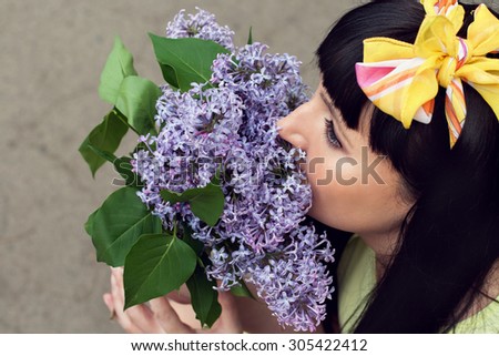 Close up beauty portrait  of young girl smelling a lilac flowers grayn background