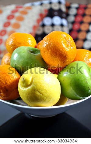 Mandarins, oranges, apples and lemons in a ceramic bowl, on a home background