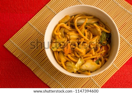 Fried noodle.  Yakisoba with beef, ticken and vegetables in a white bowl on a red background. Asian cuisine meal. Stock foto © 