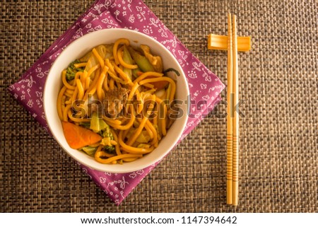 Fried noodle.  Yakisoba with beef, ticken and vegetables in a white bowl on a dark background. Asian cuisine meal. Stock foto © 