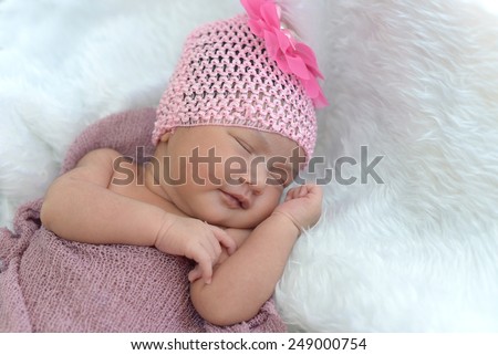 Cute asian baby girl sleeping on white furry cloth wearing pink headband