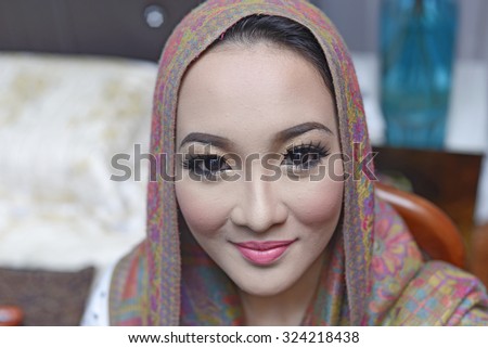 Young beautiful bride applying wedding make-up by make-up artist. malay wedding ceremony. islamic bride