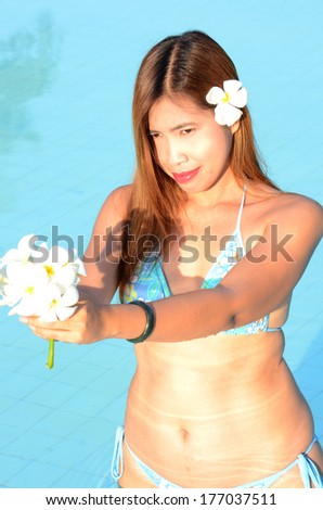 Long hairs beautiful lady in swimming pool and white flowers in her hand