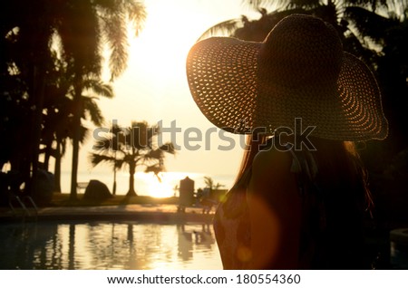 Beautiful long hairs lady in long dress and big beach hat on her morning relax vacation.