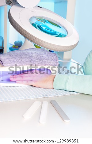 Nail salon, a female hand inside drying UV light machine