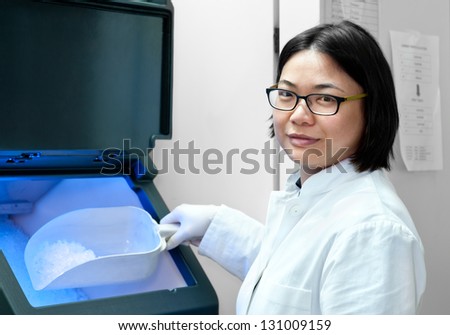 Chinese scientist or tech with scoop full of ice by ice machine in research institute
