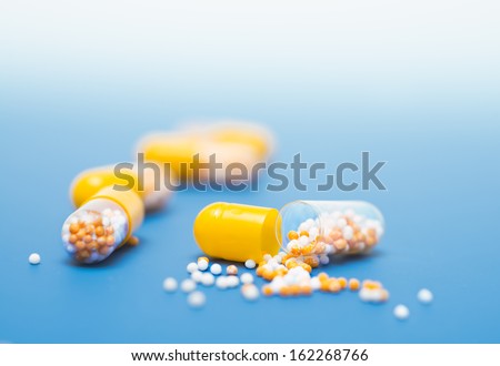 Yellow capsules on blue background, one split open, text space