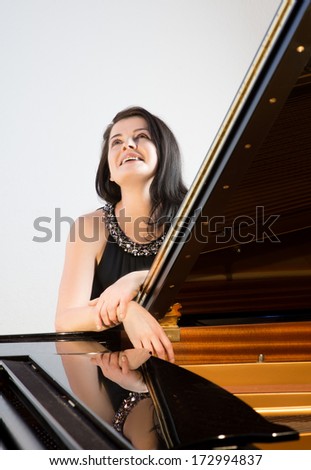 Smiling musician by grand piano looking up, text space