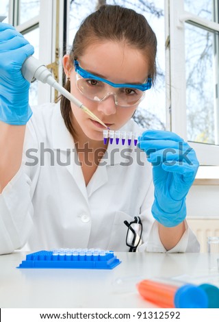 Modern laboratory; young researcher in white coat loads pcr samples to test DNA