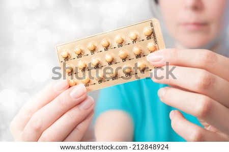 Young woman holds birth control pills