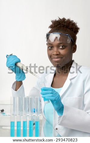 African-american scientist or graduate student in lab coat and protective wear works with liquid sample