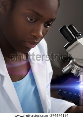 African-american scientist, medical worker, tech or graduate student works with microscope. Artificial microscope light and a flare were added to the picture. Focus on the front eye.