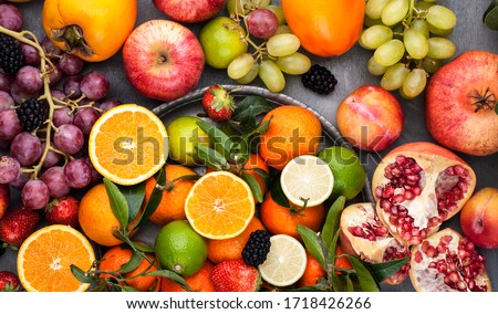 Assorted fruits. Different fruits on a gray background, the whole surface is covered with citrus fruits, pomegranates, apples, grapes, strawberries. Top view