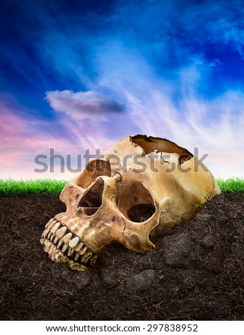 Broken human skull bury underground on fantasy sky background in concept of die