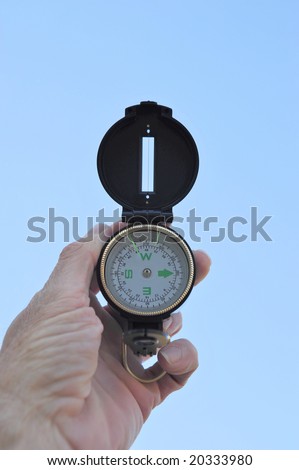 A black lensatic compass and light blue sky