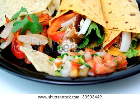 Grilled teriyaki chicken, red bell pepper, white onion, cilantro and romain lettuce are used to fill the tomato and basil wraps with grilled veggies and fresh tomato salsa and chips on the plate