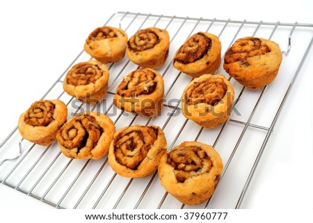 Small cinnamon rolls cooling a silver metal rack after baking in the oven