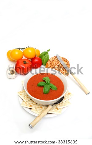 Bowl of tomato soup with crackers and a roll with  fresh tomatoes isolated on a white background