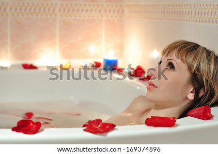 A girl takes a bath in the foam and in the rose petals