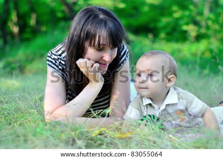 Family on a grass. Mum looks at the son. The son looks afar
