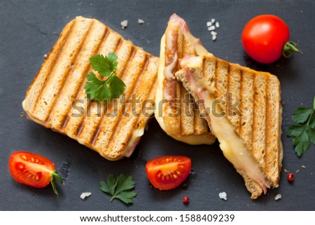 Top view photo of a club sandwich. Toasted sandwiches with salami and melted cheese on black background. 