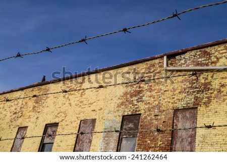 The barbed wire with old brick building in background.