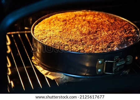 Fresh homemade pie in a special baking dish in an electric oven in the kitchen. View of a baked hot pie with the oven door open. Delicious apple dessert cake. Сток-фото © 