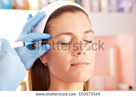 Woman in beauty clinic getting botox injection to remove eye wrinkles